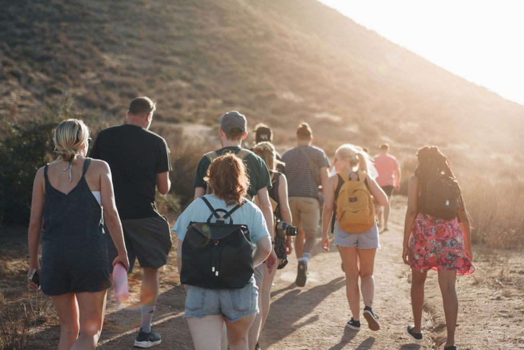 A small group walking along a dirt road toward the mountains