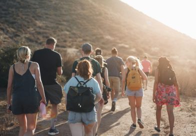 A small group walking along a dirt road toward the mountains
