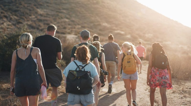 A small group walking along a dirt road toward the mountains