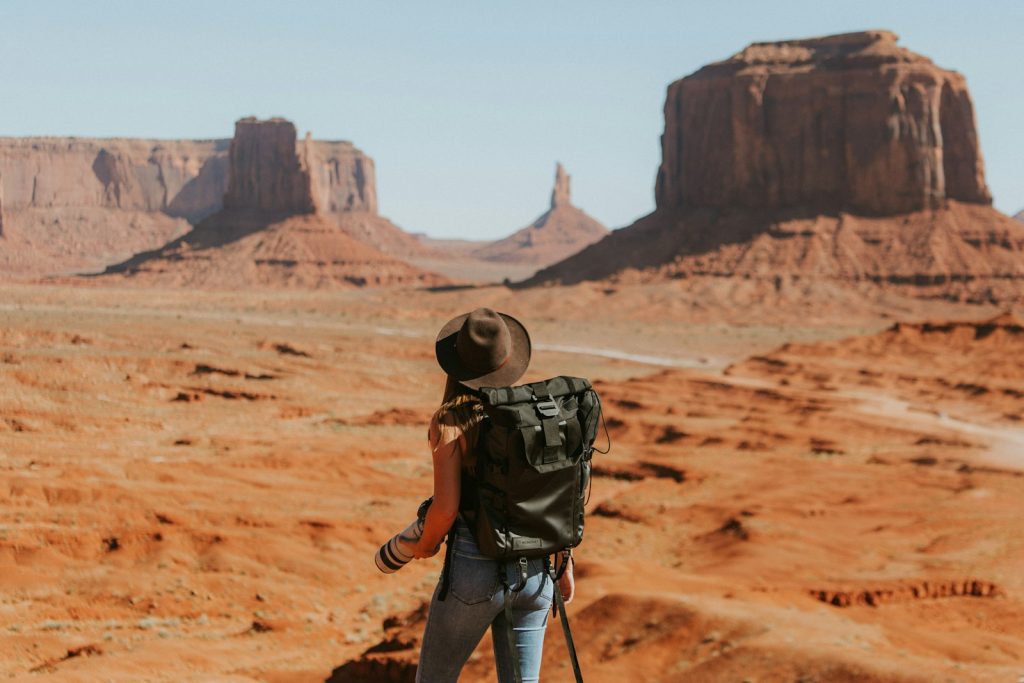 A solo traveler with a backpack looking out over a desert landscape
