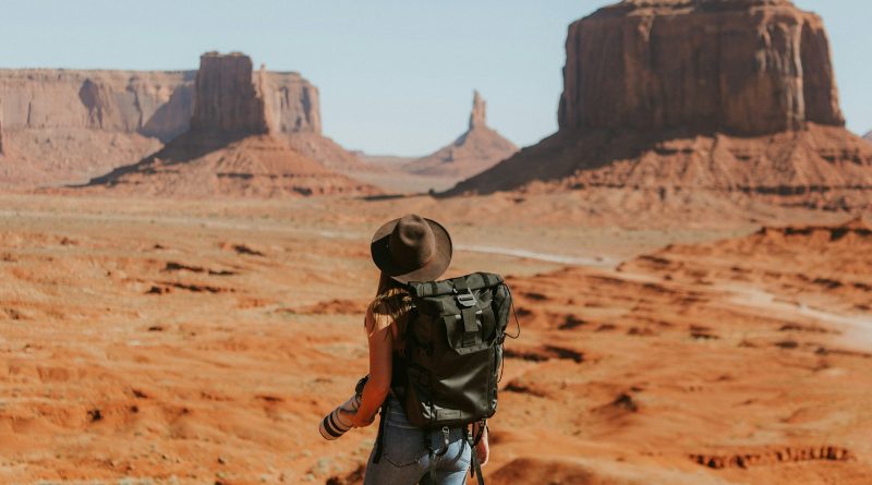 A solo traveler with a backpack looking out over a desert landscape