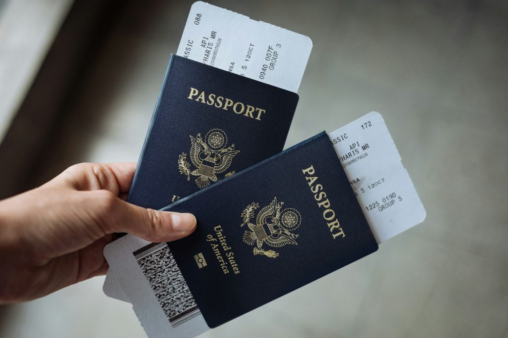 A hand holding two passports with boarding passes tucked inside
