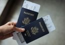 A hand holding two passports with boarding passes tucked inside