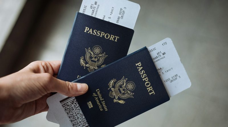 A hand holding two passports with boarding passes tucked inside