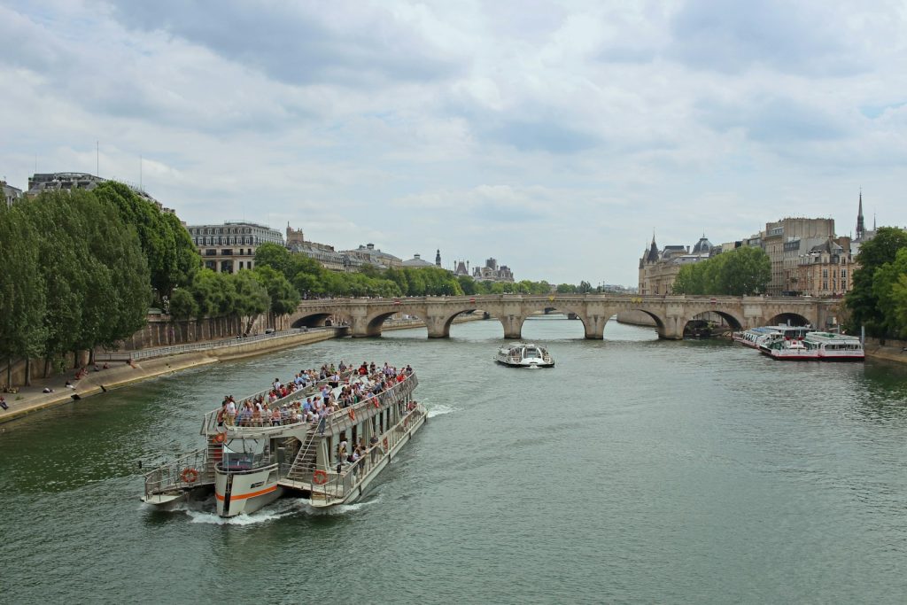 A river cruise boat heading toward a stone bridge