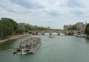 A river cruise boat heading toward a stone bridge