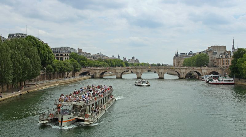 A river cruise boat heading toward a stone bridge