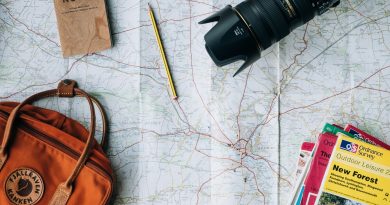 A travel map, camera, notebook and bag laid out on a table
