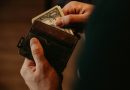 A hand placing a banknote into a leather wallet