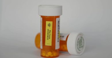 Two orange prescription pill bottles with white caps, one labeled with a warning that it may cause drowsiness.